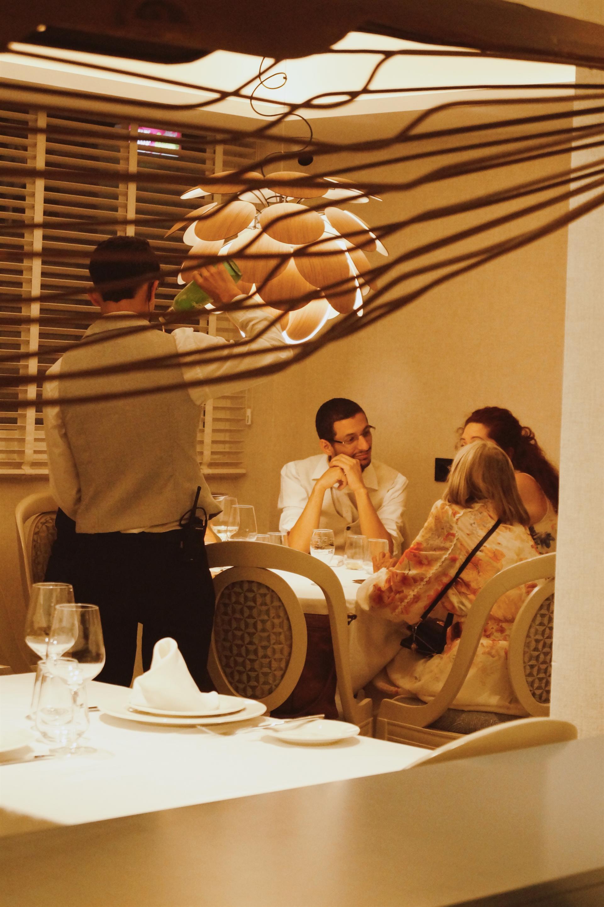 Camarero atendiendo a comensales en la sala del restaurante