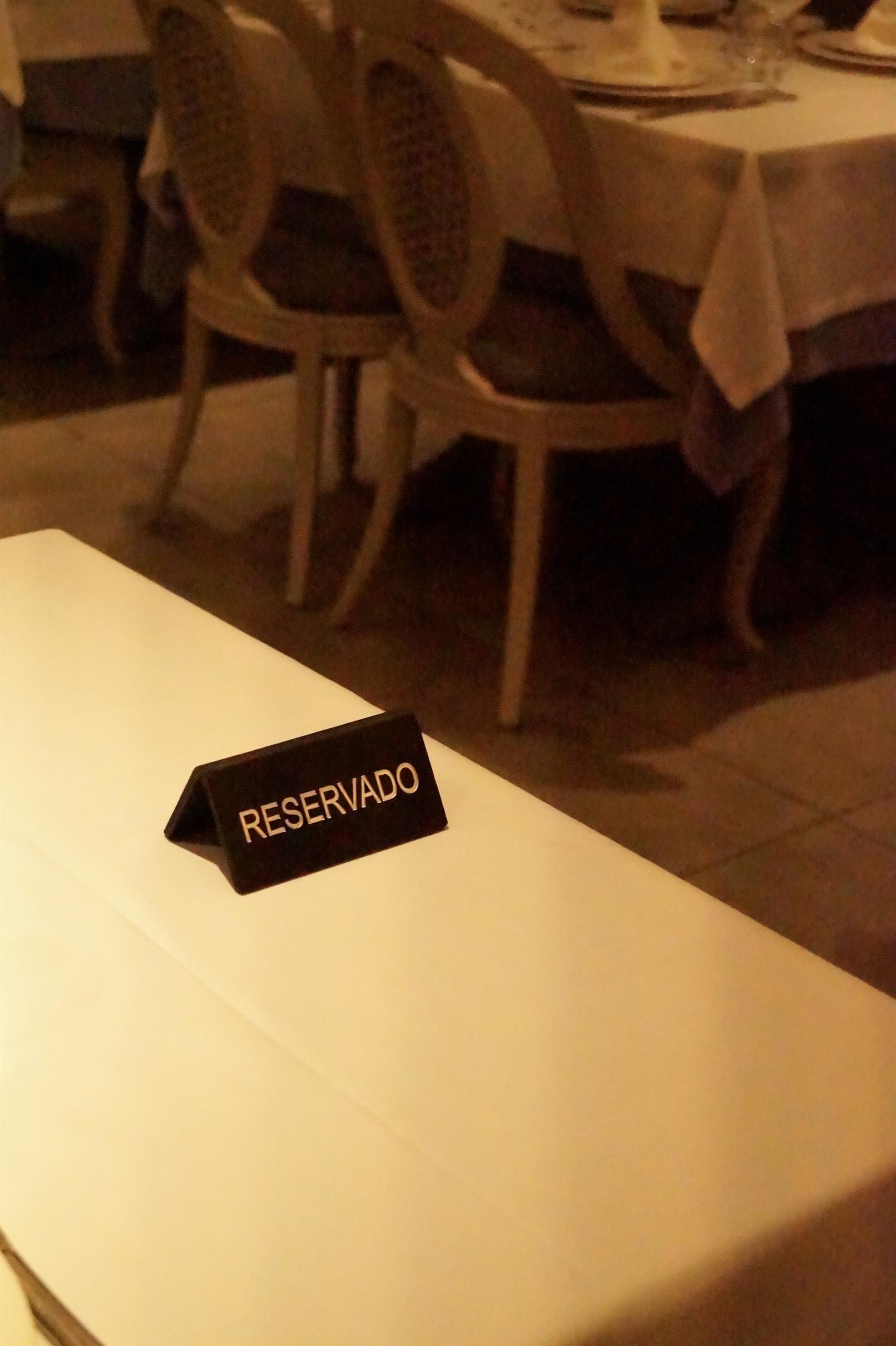 Mesa redonda con cartel RESERVADO sobre mantel blanco